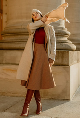 a lady in a red sweater, a brown plaid skirt and a beige wool coat